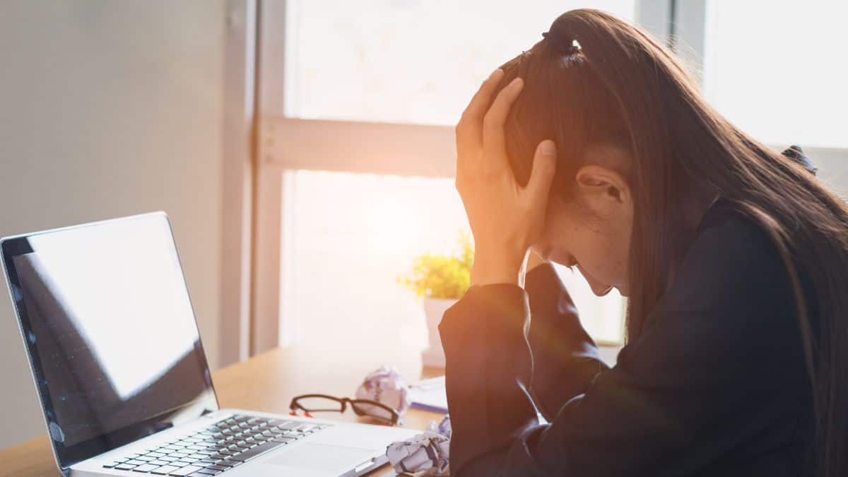 A photo of a woman looking defeated while working in front of her laptop