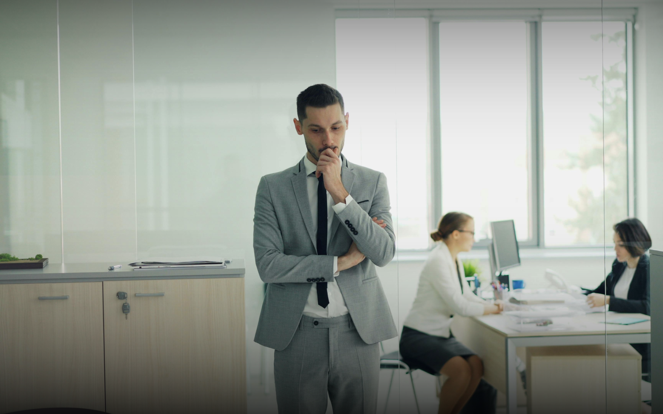 A thoughtful executive reflecting on leadership strategies in an office setting, illustrating how executive coaching facilitates decision-making and emotional intelligence.